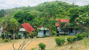 Entorno rural con casas de techos rojos, rodeado de exuberante vegetación y colinas.