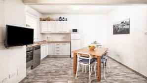 A compact kitchen with white cabinets, a microwave, and a wooden dining table with chairs. - Casa El Puerto by Huskalia (Tazacorte)