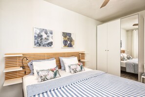 A bedroom with a wooden headboard, a bed with striped bedding, and two wall-mounted artworks. - Casa El Puerto by Huskalia (Tazacorte)