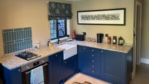 Una cocina moderna con encimera de granito, horno integrado, pileta y ventana con grifo negro.