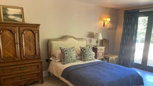 Un dormitorio con una cama, un aparador de madera, una mesita de noche y una lámpara.