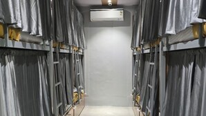 A corridor with bunk beds, a central air conditioning unit, and a tiled floor. - Classy Ac Dormitory (Mumbai)