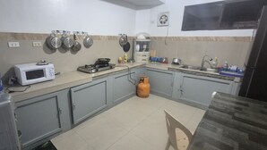 A compact kitchen with a microwave, gas stove, and a water dispenser. - Hymn's Tourist Inn (Coron)