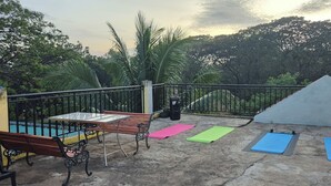 A rooftop terrace with exercise mats, a table, and benches. - Hymn's Tourist Inn (Coron)