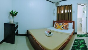A neatly arranged bedroom with a bed, bedside table, and a potted plant. - Hymn's Tourist Inn (Coron)
