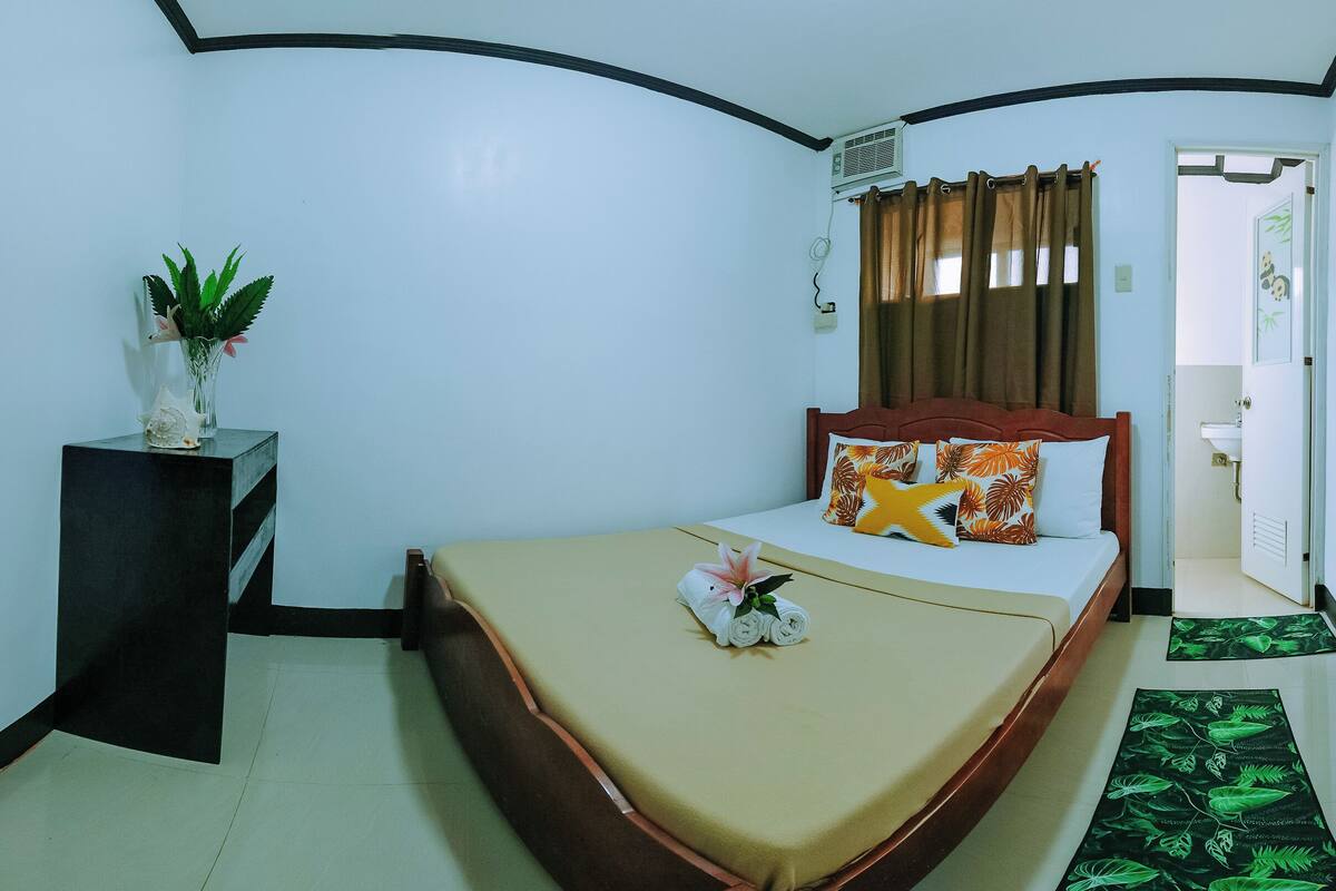 A neatly arranged bedroom with a bed, bedside table, and a potted plant.