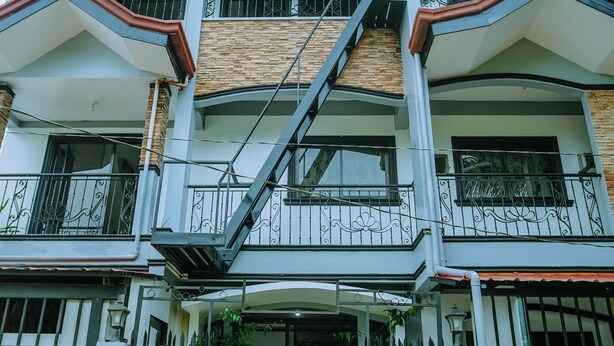 A multi-story building with a central staircase, balconies, and a gated entrance. - Hymn's Tourist Inn (Coron)