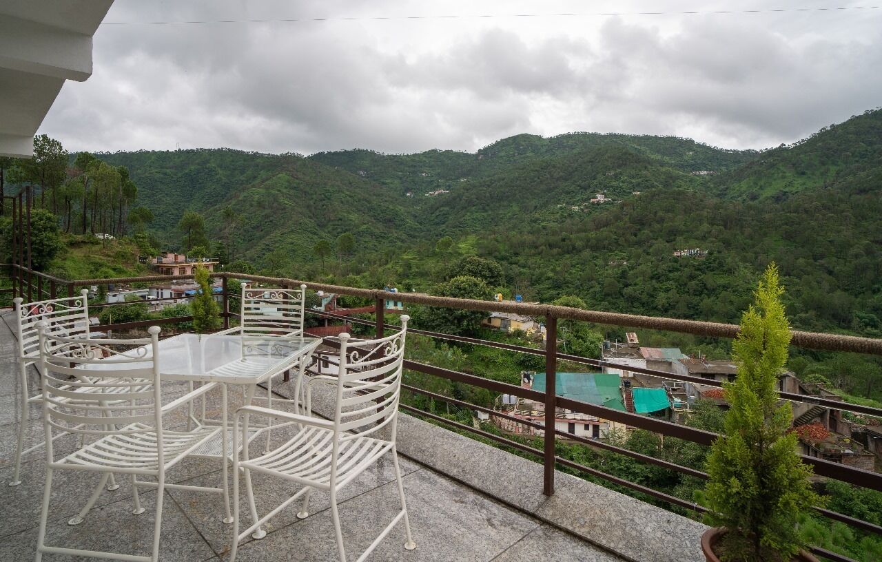 A terrace with a table and chairs overlooking a mountainous landscape.