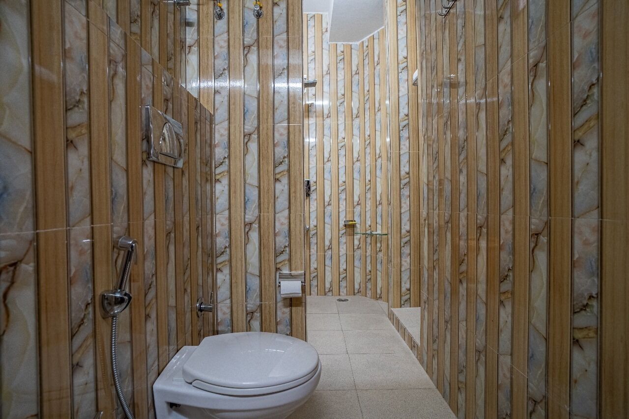 Un baño con pared de mármol, inodoro y zona de ducha.