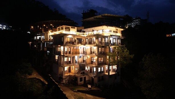A multi-story hotel with balconies and a well-lit facade at night. - Captain Resort (Kasauli)