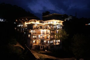 Un hotel de varios pisos con balcones y una fachada iluminada de noche.
