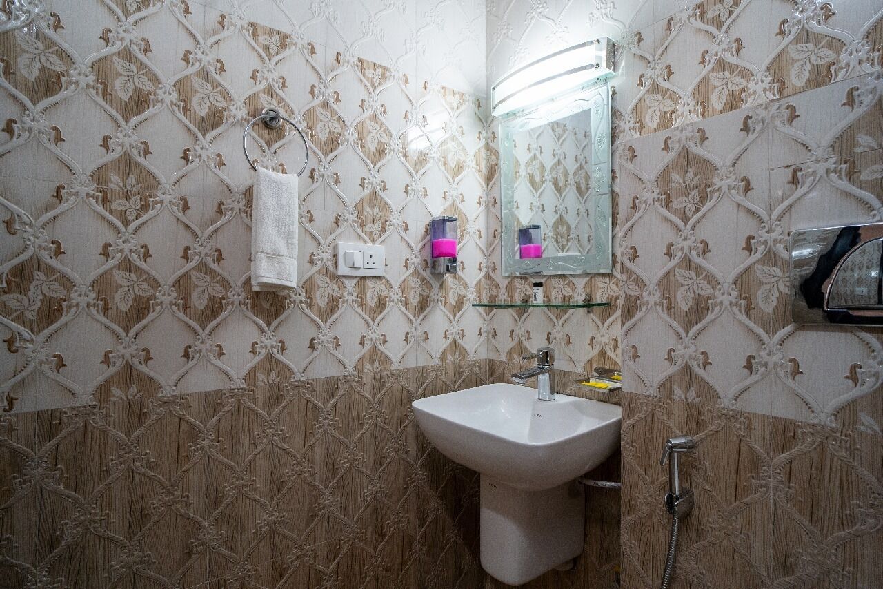 Un baño con papel tapiz estampado, un lavabo blanco, un espejo y un perchero para toallas.
