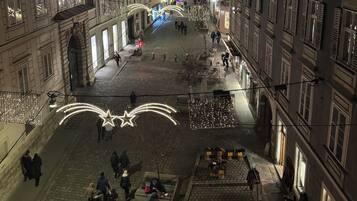 A cobblestone street with historic buildings, illuminated by decorative lights and star-shaped decorations.