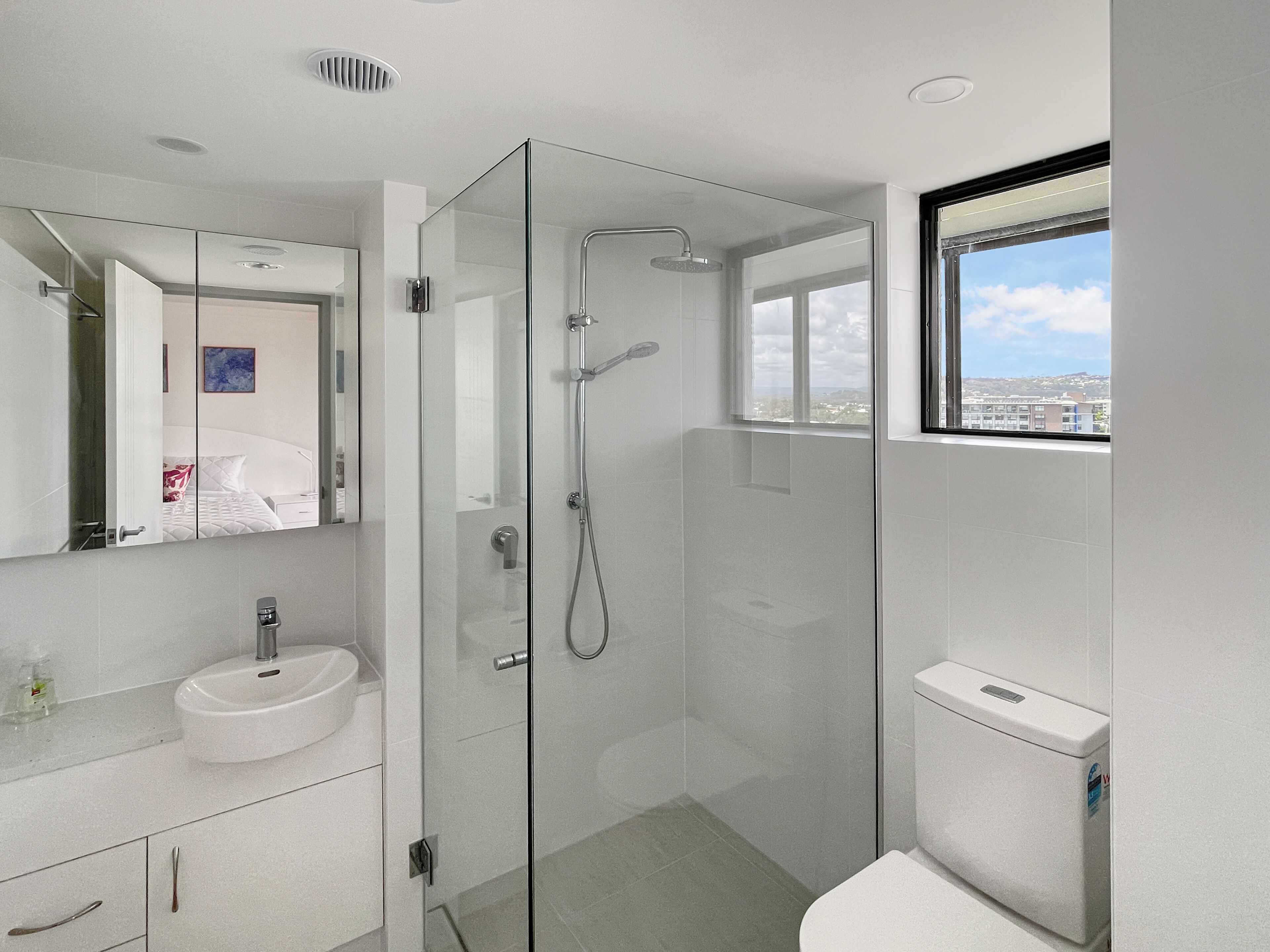 A modern bathroom with a glass-enclosed shower, a white sink, and a toilet.