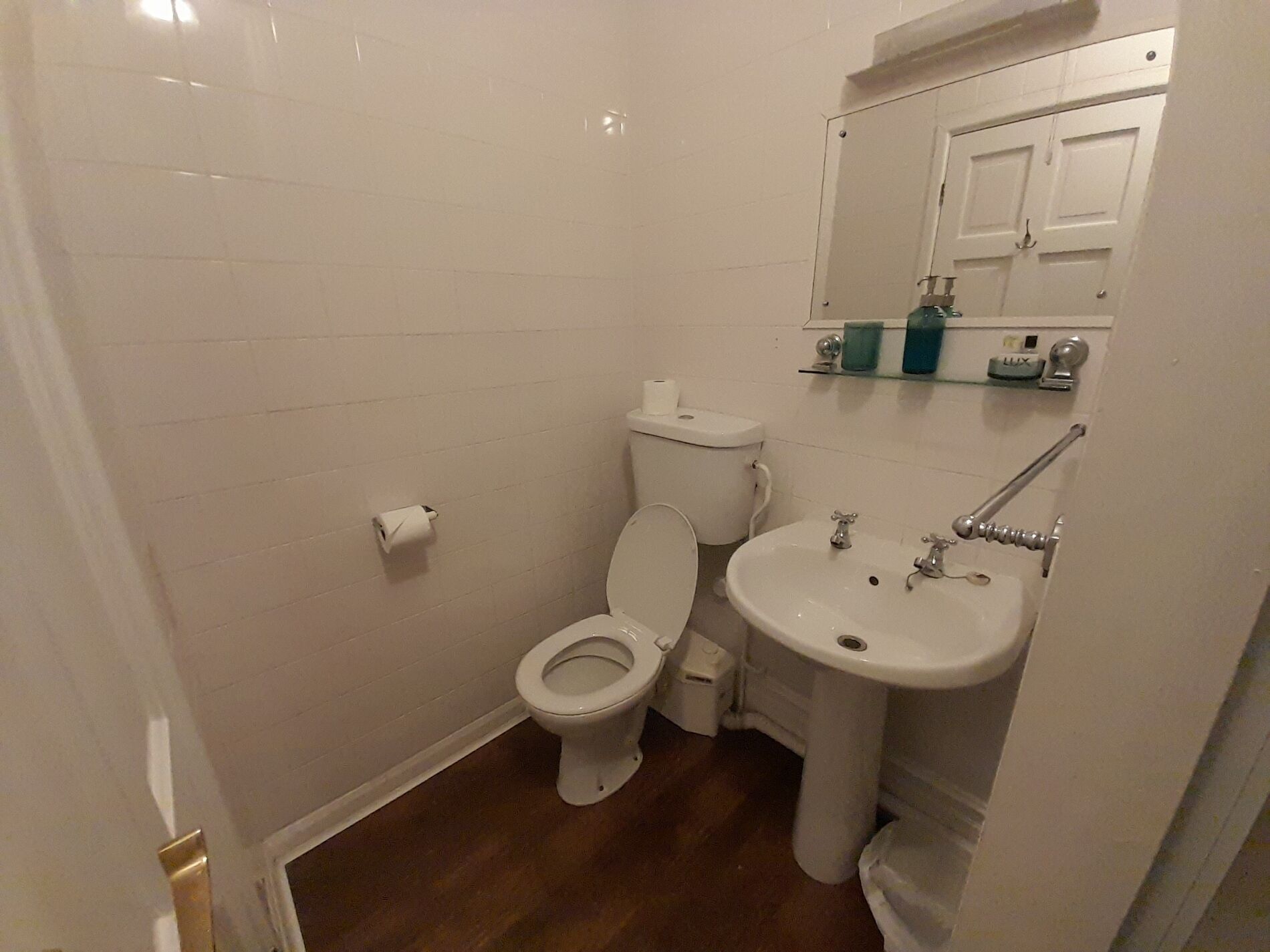 A small, clean bathroom with a toilet, sink, and mirror.