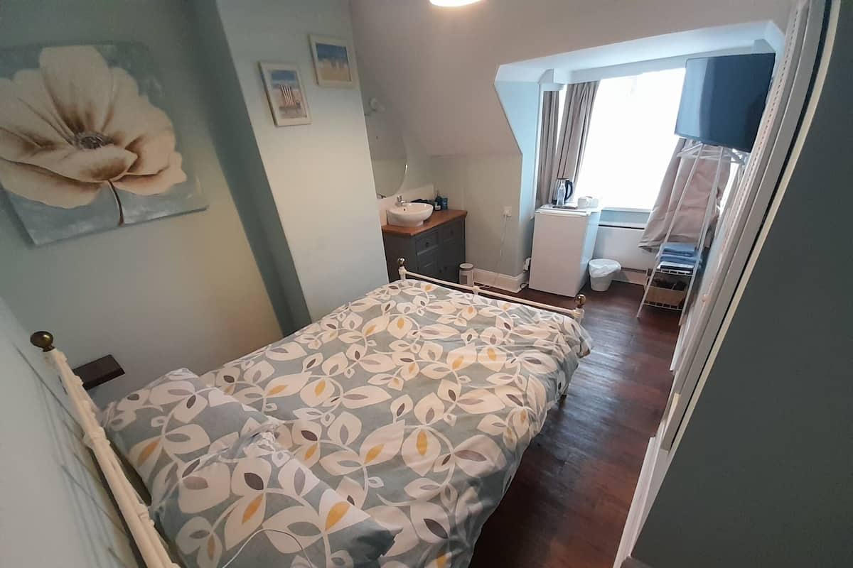 A bedroom with a bed, a dresser, a mirror, and a window with curtains.