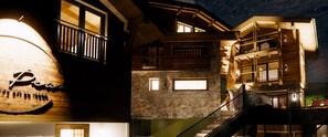 Experience the charm of this rustic hotel with exposed beams and a stone facade, featuring multiple balconies and a grand staircase.