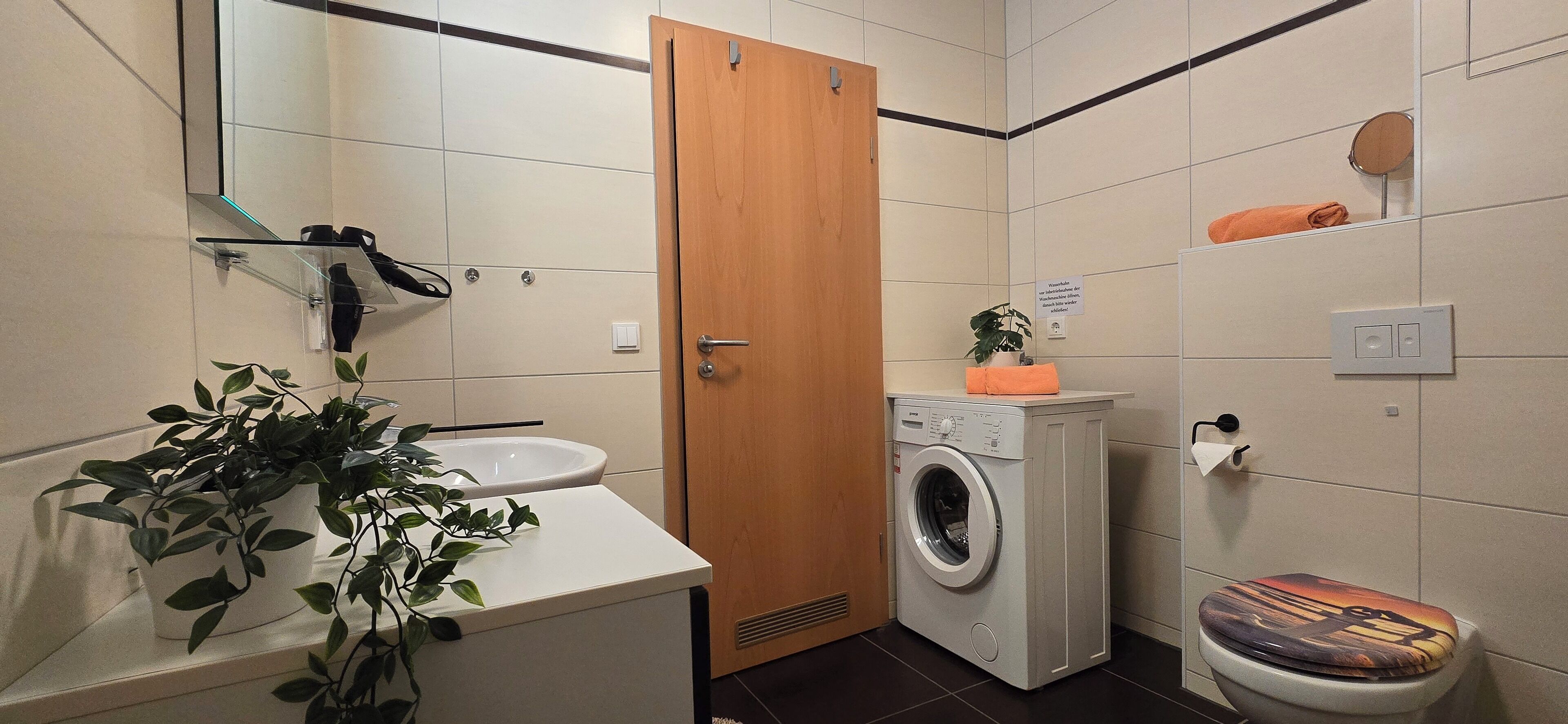 Un baño pequeño con lavabo, lavadora, inodoro y espejo.