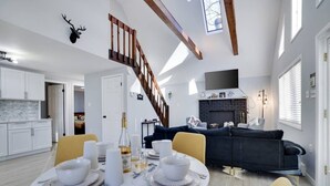 A modern living space with a dining area, kitchen, and a fireplace. - The Cozy Modern Cabin – Ski & Relax (Tobyhanna)
