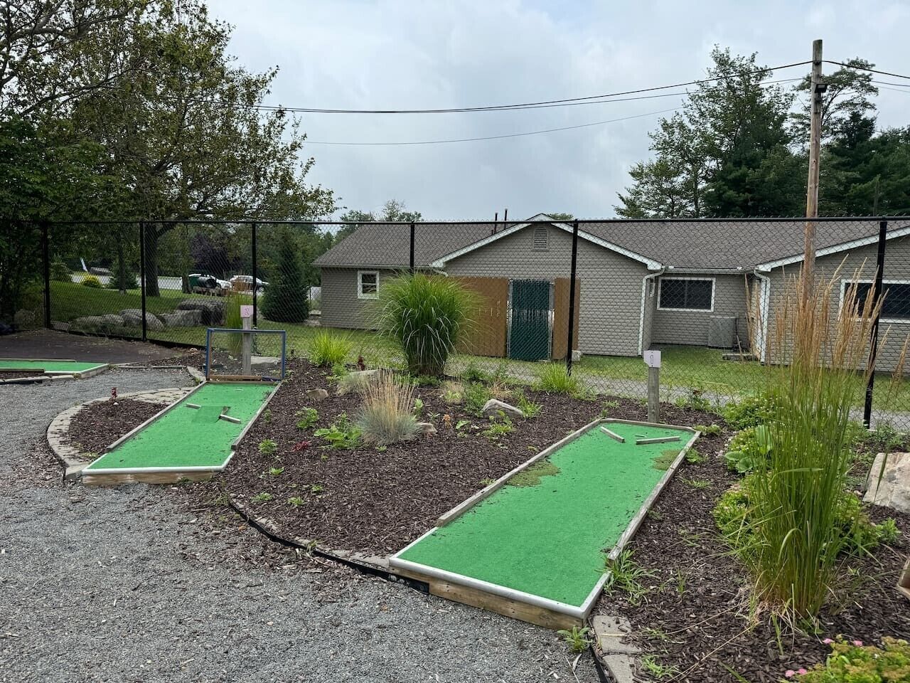 A mini-golf course with a gravel path and green artificial turf.