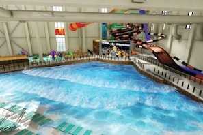 An indoor water park with a wave pool, a water slide, and a viewing area with spectators. - The Cozy Modern Cabin – Ski & Relax (Tobyhanna)