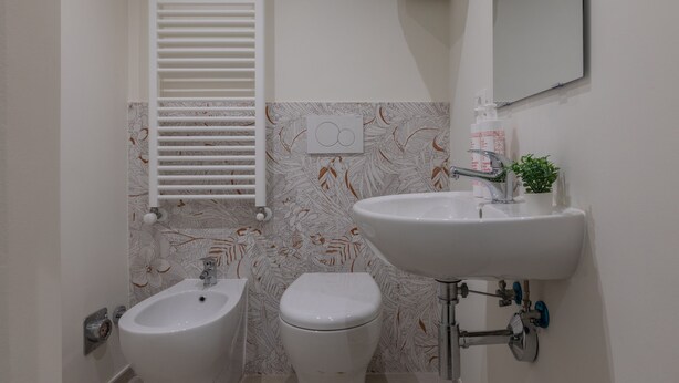 Un bagno con bidet, water, lavandino e porta asciugamani.