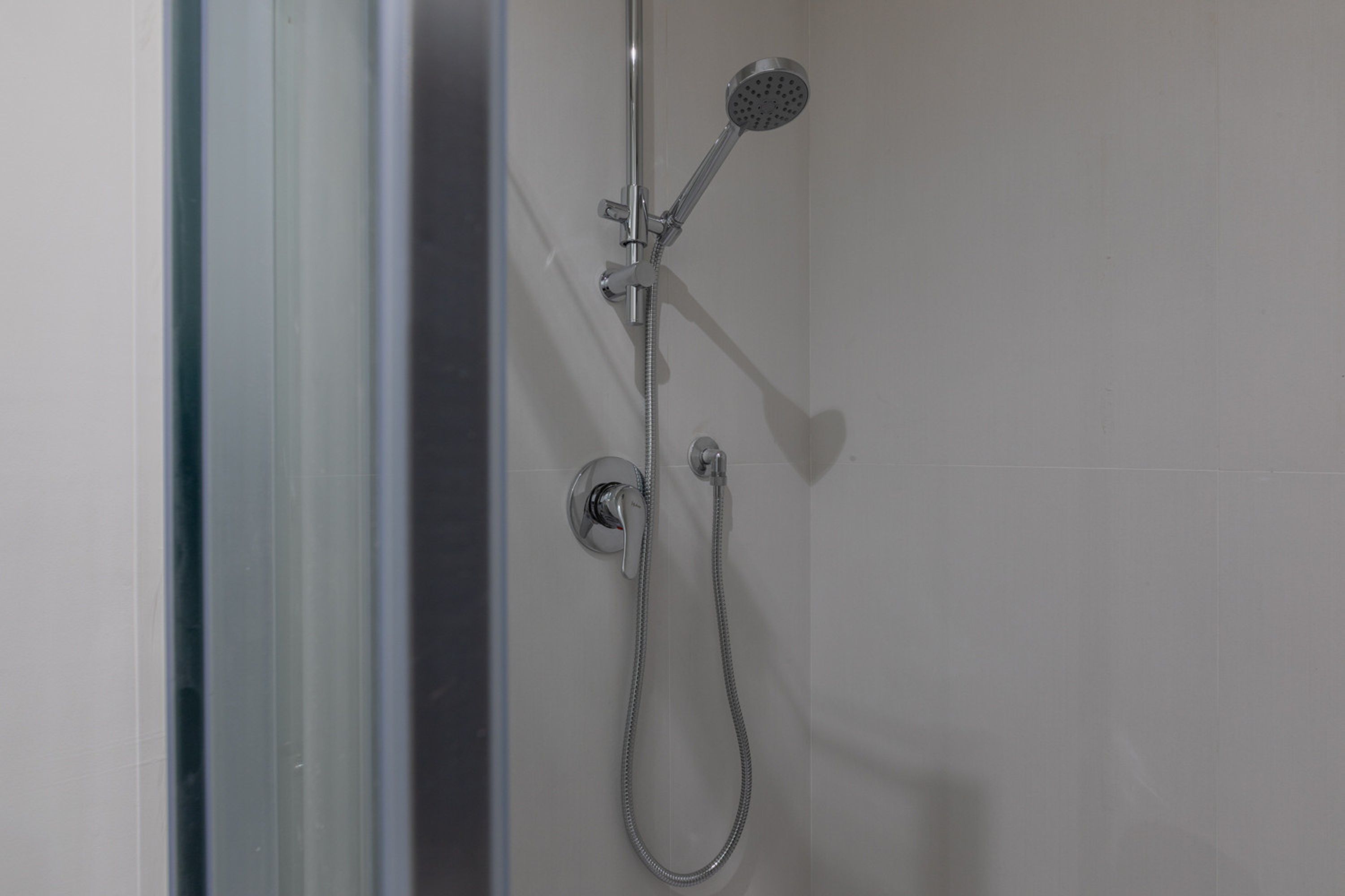 Une douche équipée d’un pommeau de douche à main et d’un pommeau de douche fixe, tous deux fixés au mur.
