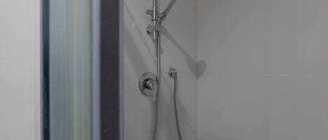 Une douche équipée d’un pommeau de douche à main et d’un pommeau de douche fixe, tous deux fixés au mur.