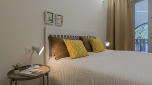 Un letto rifatto con cura, una testiera a righe, un comodino con una lampada e due quadri appesi al muro.