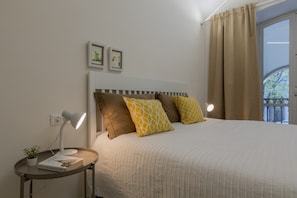 A neatly made bed with a striped headboard, a bedside table with a lamp, and two framed pictures on the wall.