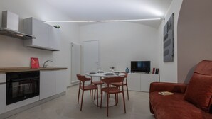 A modern kitchen with white cabinets, a built-in oven, and a dining area with a round table and chairs. - Ai Portici di Susa - Classy by Wonderful Italy (Turin)