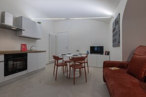 Eine moderne Küche mit weißen Schränken, einem eingebauten Backofen und einem Essbereich mit rundem Tisch und Stühlen.