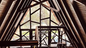 A high-ceilinged, triangular room with exposed wooden beams and large windows. -  Otelox Sinap Bungalow  (Erdemli)