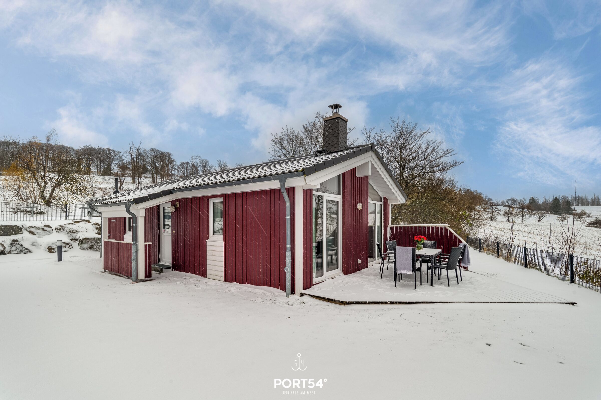 A red wooden building with a covered patio and a chimney.