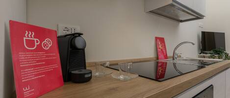 A modern kitchen with a coffee machine, a sink, and a red sign with text.