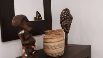 A small shelf with a sculpture, a woven basket, and a mirror.