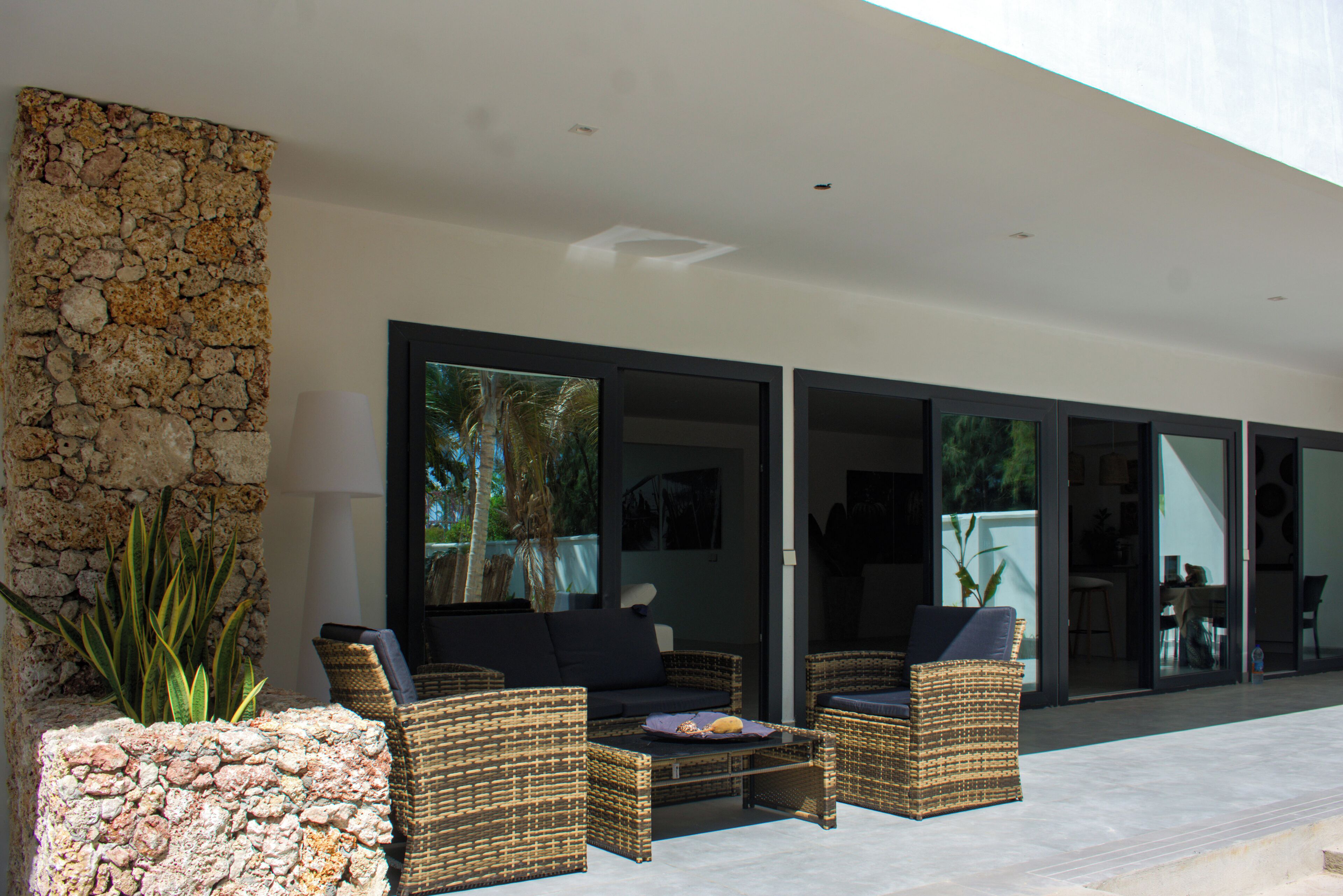 An outdoor seating area with wicker furniture and a stone wall.