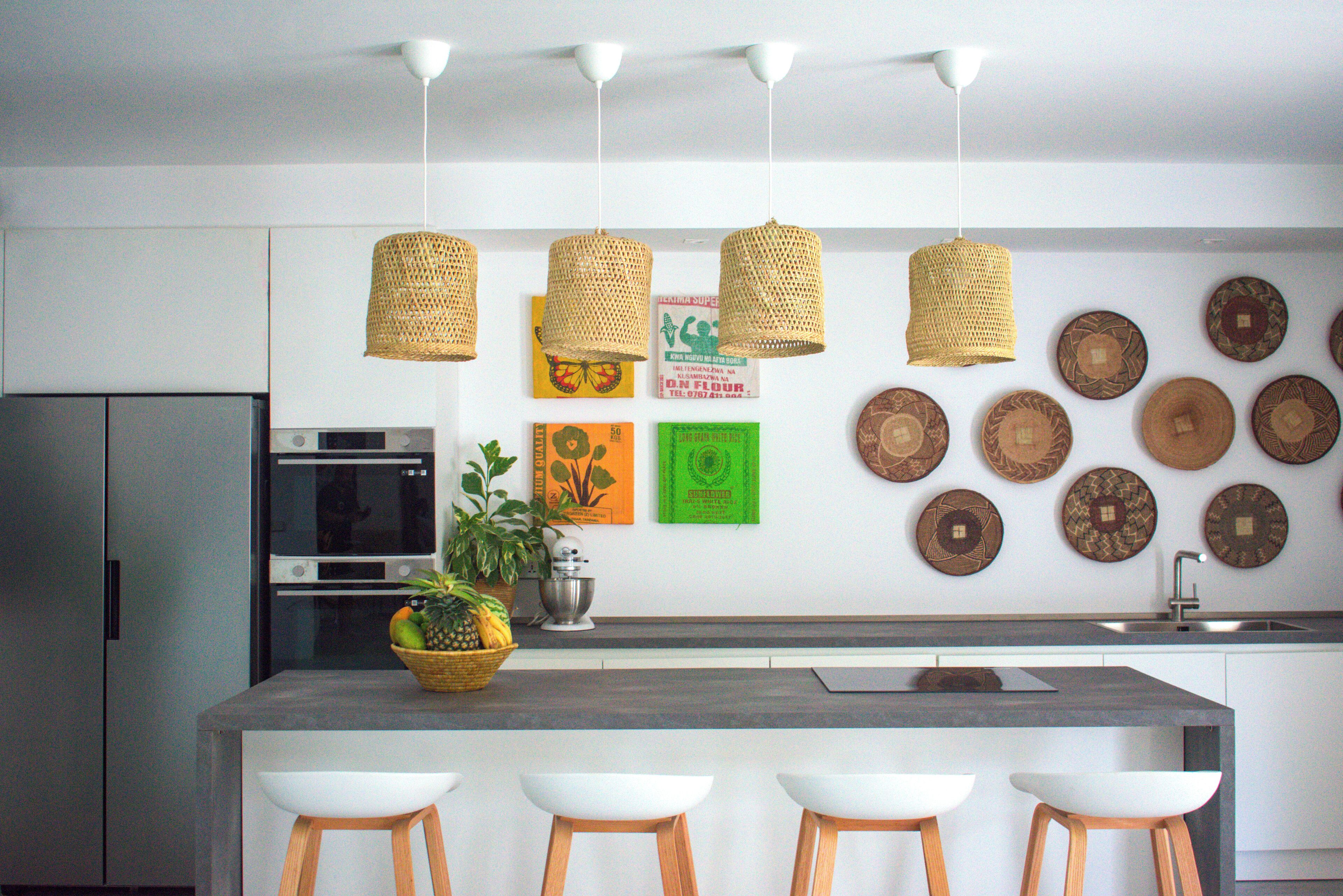 Een moderne keuken met een centraal eiland, barkrukken, een koelkast, een oven en decoratieve borden aan de muur.