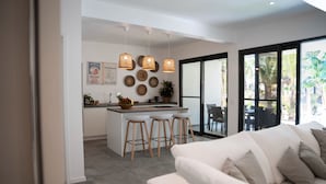 A modern kitchen with a central island, bar stools, and pendant lights. - The Oasis Residence (Jambiani)