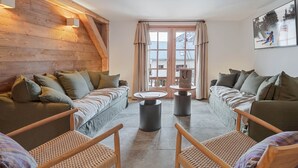 Un salon chaleureux avec un plafond en bois, deux canapés, une table basse et un fauteuil en osier.
