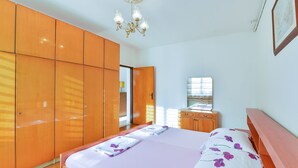 A bedroom with a bed, wooden wardrobe, and a chandelier. - Apartment Basic Mario (Vir)