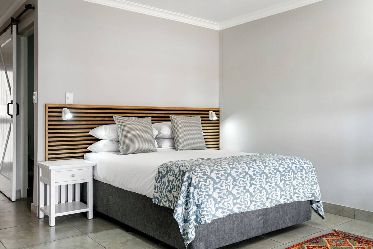 A bedroom with a wooden headboard, a bedside table, and a patterned bedspread.