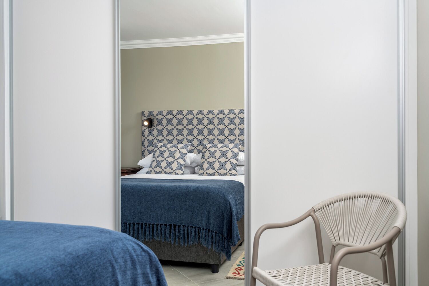 A bedroom with a bed, a chair, and a patterned headboard.