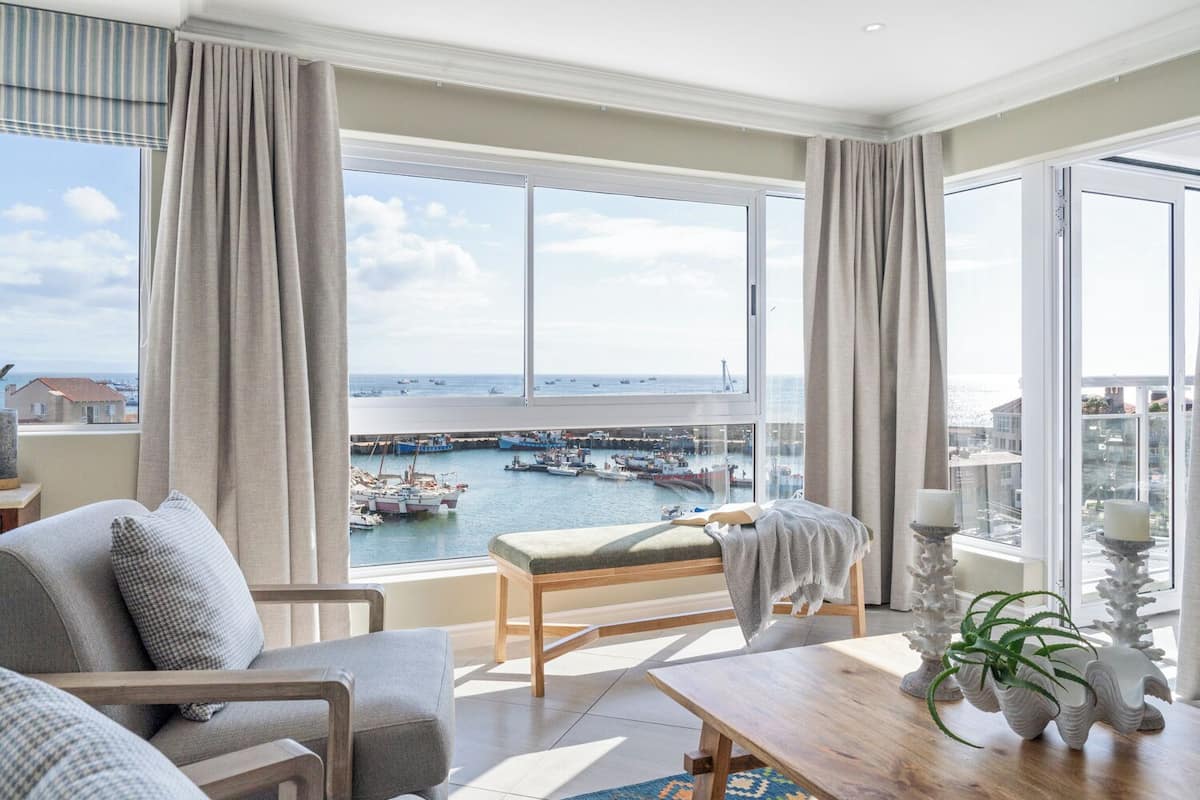 A spacious living room with a large window offering a view of a marina and boats.