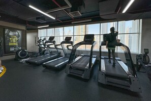 Et fitnesscenter med løbebånd, spinningcykler og et stort vindue med udsigt over byen.