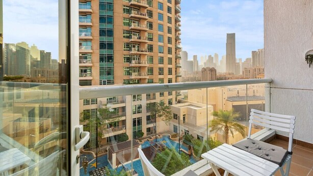 A high-rise building with multiple balconies and a view of a cityscape.
