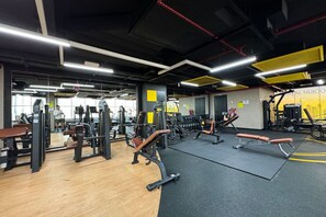 Ein Fitnessstudio mit unterschiedlichen Trainingsgeräten, Spiegeln und Holzboden.
