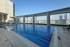 Ein Dachpool mit klarem, blauen Wasser, umgeben von einer modernen Architektur mit großen Fenstern und Blick auf die Stadtlandschaft.