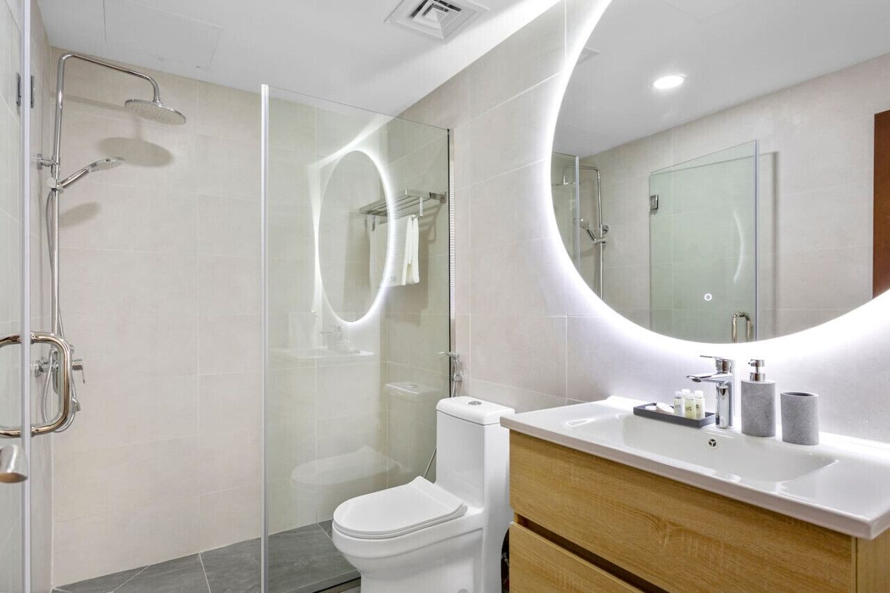 A modern bathroom with a glass-enclosed shower, a white toilet, a vanity with a mirror, and a sink.