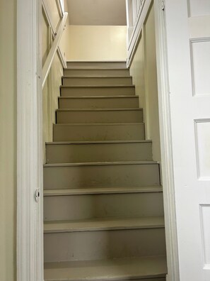 A staircase with a handrail, leading to a landing with a door.